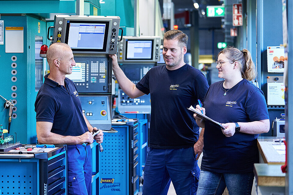 Drei Mitarbeiter von heinrichs stimmen sich in der Produktionshalle ab