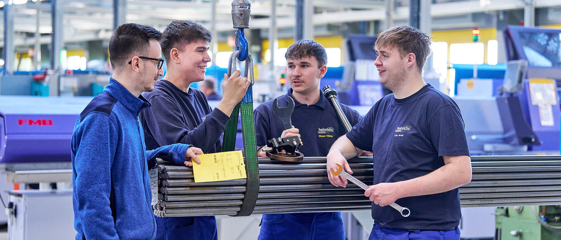 Drei Azubis von heinrichs drehteile stehen an Stahlrohren