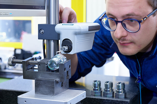 Mitarbeiter bei der Kontrolle von Drehteilen