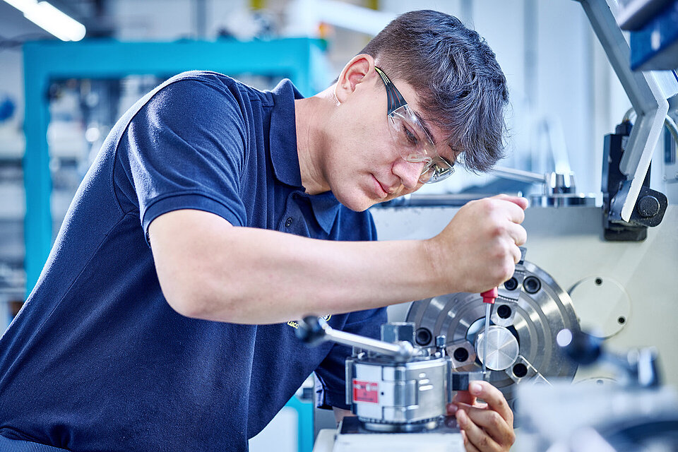 Auszubildener von heinrich wechselt das Werkzeug an einer Drehmaschine