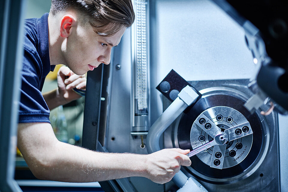 Azubi beim Einspannen eines Werkstücks in eine CNC-Drehmaschine